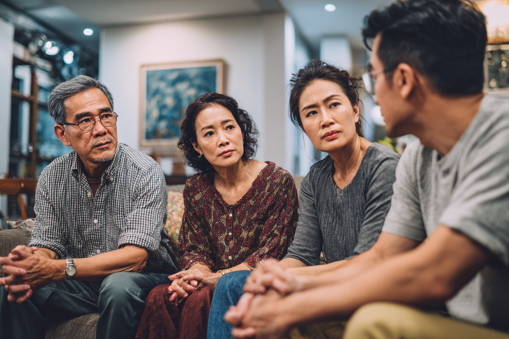 Overwhelmed siblings experiencing family digital caregiver burden while helping elderly parent