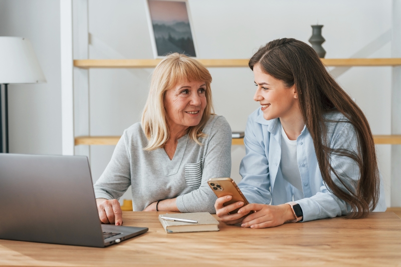 Adult daughter helping elderly mother with digital accounts and technology planning