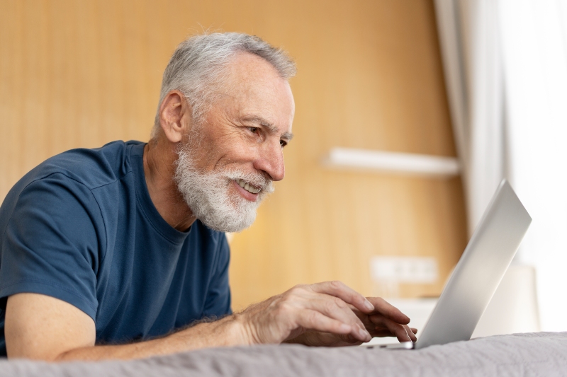 Confident mature man with beard working on laptop computer