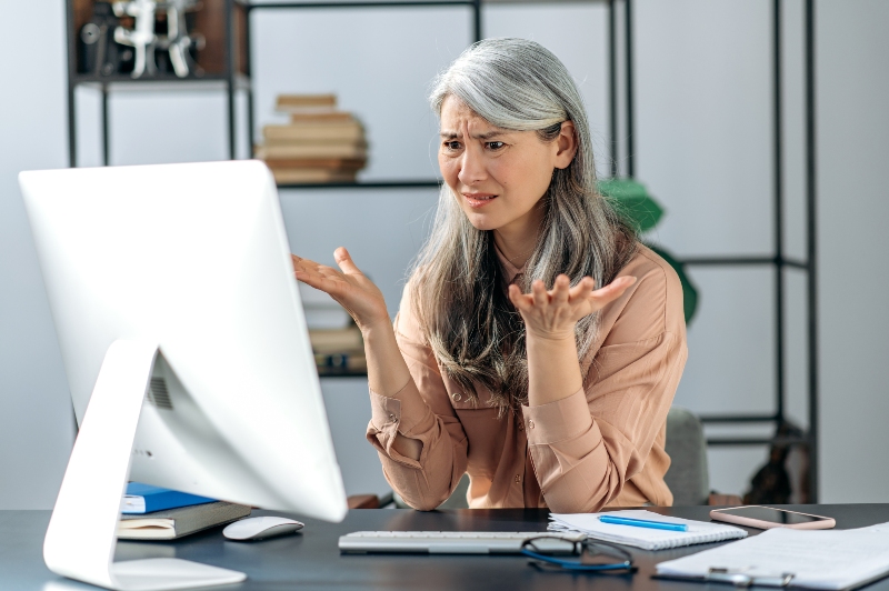 Older woman stressed by the cost of digital disorganization at her computer